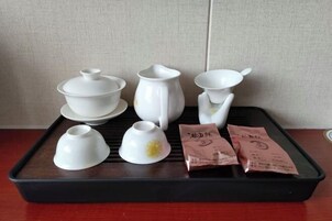 Una bandeja con juego de té de cerámica blanca, que incluye tetera, tazas y platillos, junto a dos bolsitas de té.