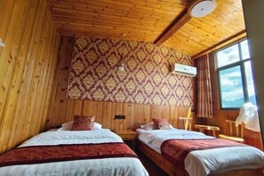 A room with wooden walls and ceiling, two beds with red and white bedding, a patterned wallpaper, an air conditioning unit, and a window with a view. - Harbor Inn She County Shendu Town (She County)