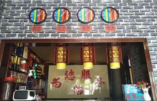 Fachada com parede de tijolos, quatro relógios e um letreiro com caracteres chineses.