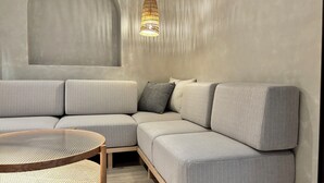 A modern living room with a grey sectional sofa, a round wooden table, and a hanging light fixture. - Hotel Initial-Tainan (Tainan)