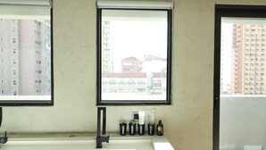 A bathroom with a sink, two windows, and a view of buildings. - Hotel Initial-Tainan (Tainan)