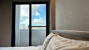 A hotel room with a bed, a window with a view of buildings, and a door. - Hotel Initial-Tainan (Tainan)
