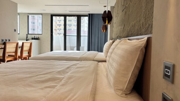 A hotel room with two beds, a dining area, and a view of the city through large windows. - Hotel Initial-Tainan (Tainan)