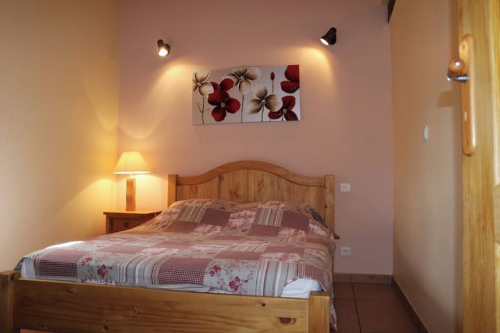 Une chambre à coucher avec un lit en bois, une table de chevet avec une lampe et une œuvre d’art florale accrochée au mur.