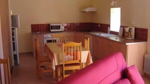 A compact kitchen with a dining area, a microwave, and a sink. - Ferme en Cévennes (Aulas)