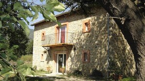 A stone house with a balcony, a door, and a small window. - Ferme en Cévennes (Aulas)