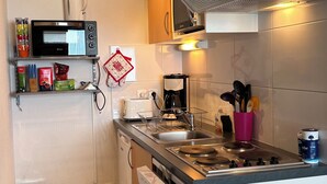 A compact kitchen with a microwave, toaster, coffee maker, and a sink. There are cabinets, a trash can, and a dishwasher. - Appartement 6 Places à 150m des Pistes (Arette)