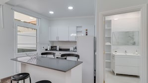 A modern kitchen with white cabinets, a central island with stools, a refrigerator, and a microwave. - Funchal City Nest I (Funchal)