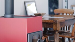 Un radiateur rouge doté d’un panneau de commande, une table à manger en bois et une chaise.