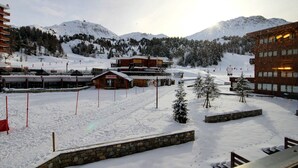 Ein verschneites Skigebiet mit Gebäuden, darunter eine Berghütte und ein Skiliftbereich.