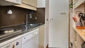 Ett kompakt kök med en inbyggd mikrovågsugn, en diskho i rostfritt stål och en diskmaskin.