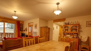 A wooden dining room with a large table and chairs, wooden cabinets, and a chandelier. - Beautiful 3-bed apartment, ski-in with wifi (Morillon 1100)