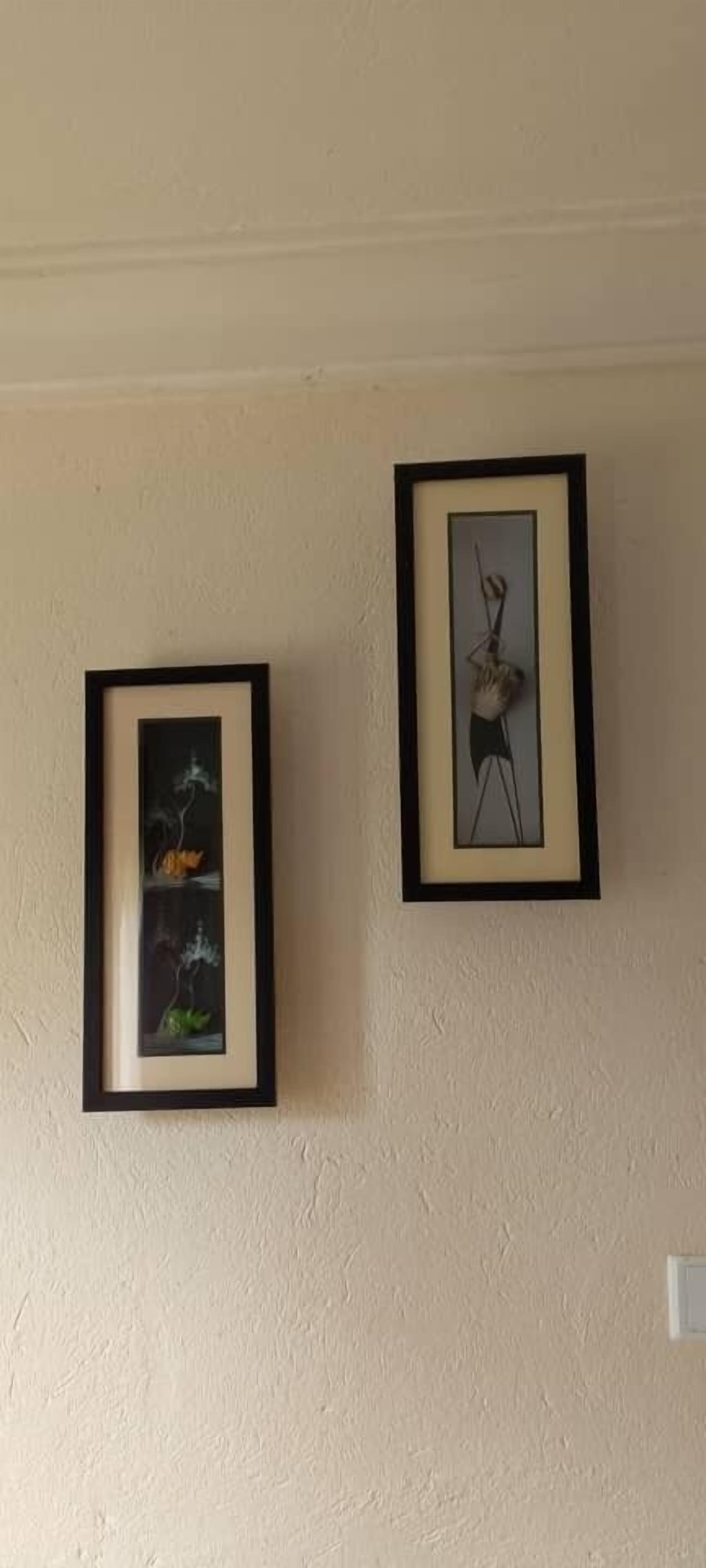 Two framed artworks on a plain wall.