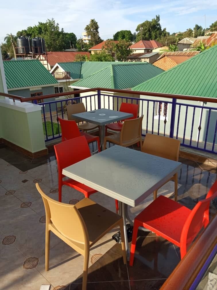 Een buitenpatio met een tafel, stoelen, een hekwerk en een uitzicht op gebouwen op de achtergrond.