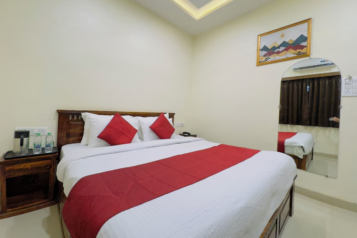 Habitación de hotel con cama, mesita de noche, espejo y un cuadro en la pared.