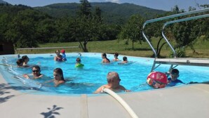 A swimming pool with people enjoying the water, surrounded by greenery and hills. - Chalet 1 en Cévennes (Aulas)