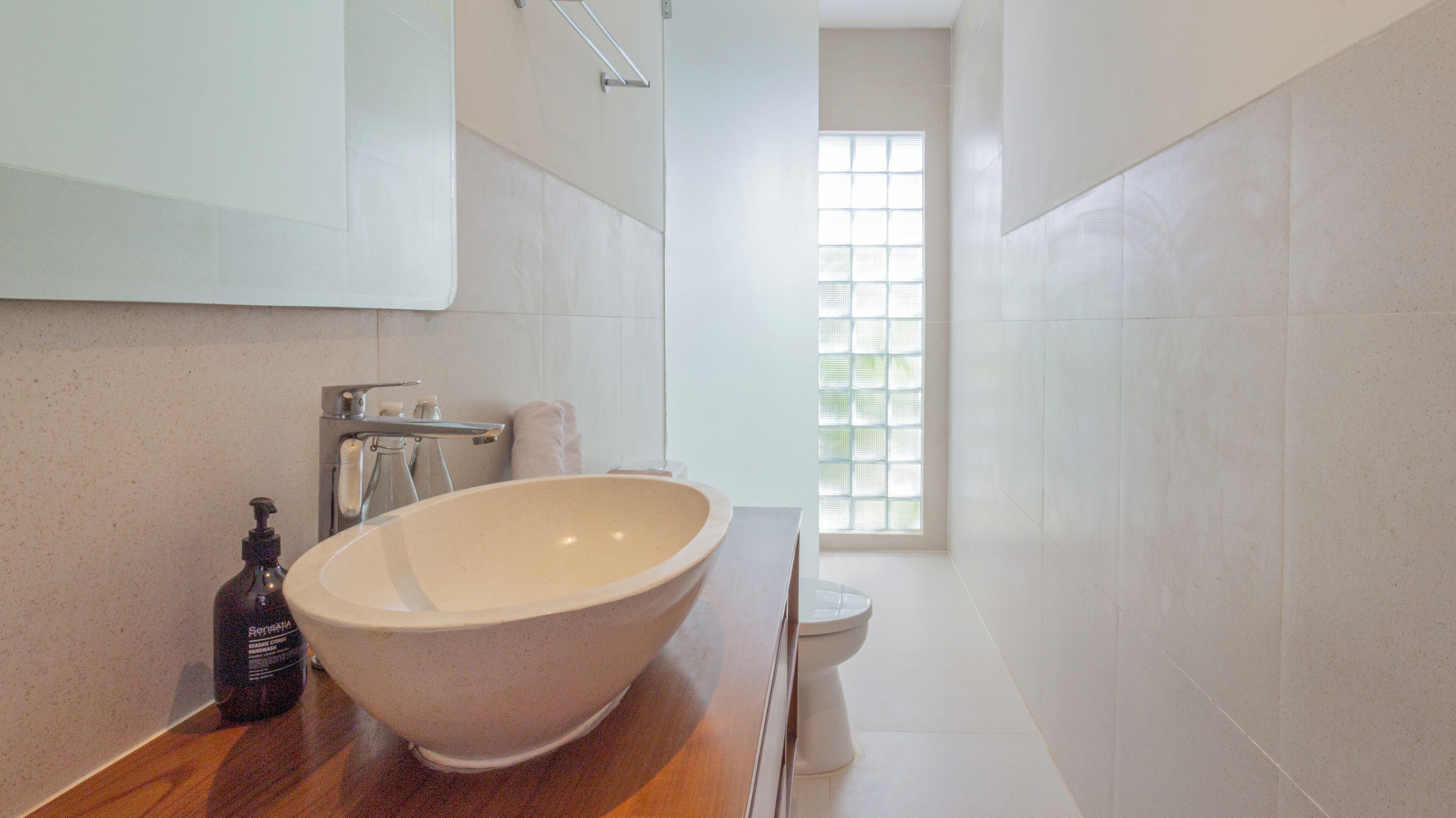 Ein modernes Badezimmer mit einer großzügigen, freistehenden Badewanne, einer Toilette und einem Fenster für natürliches Licht.