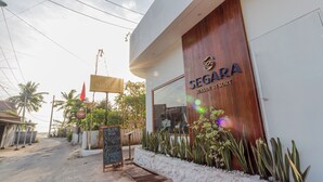 Un hotel frente al mar llamado Segara Seaside Resort con fachada de madera y un cartel.