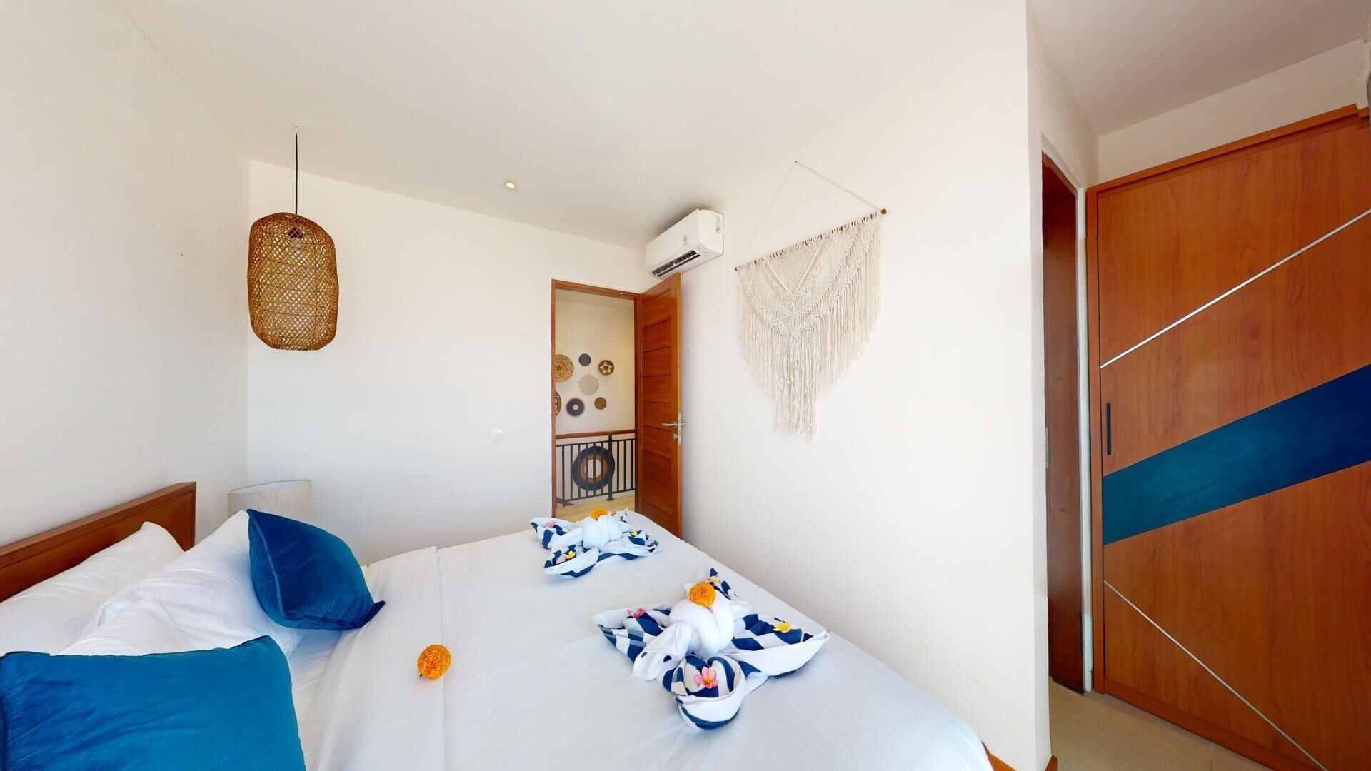 Une chambre d’hôtel équipée d’un lit, d’une armoire, d’un luminaire suspendu et d’un climatiseur fixé au mur.