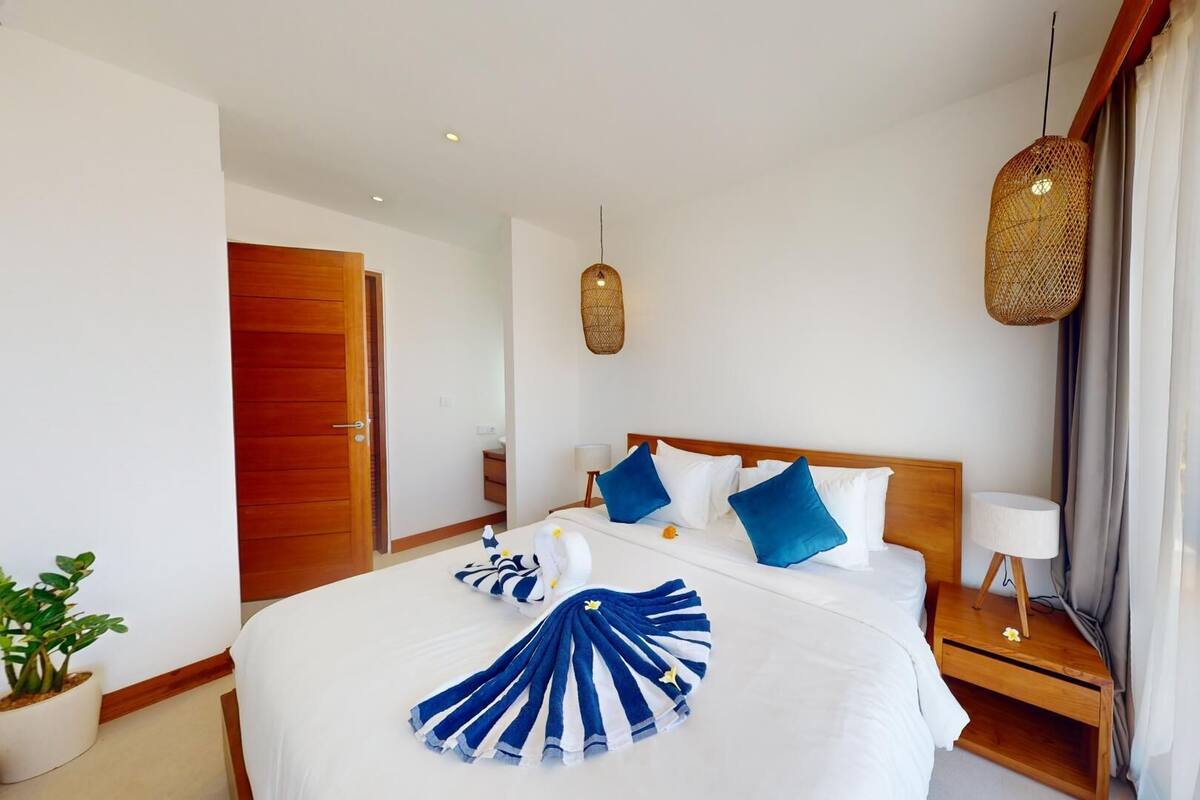 A hotel room with a large bed, wooden headboard, and a bedside table with a lamp.