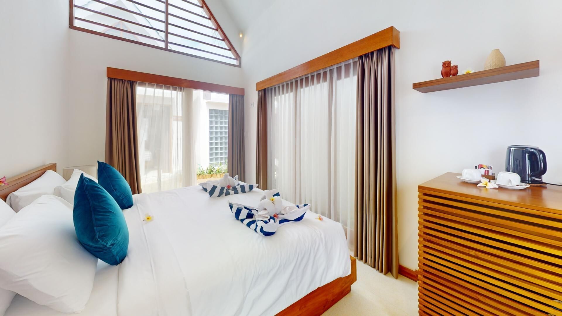 A hotel room with a large bed, a wooden dresser, and a window with curtains.