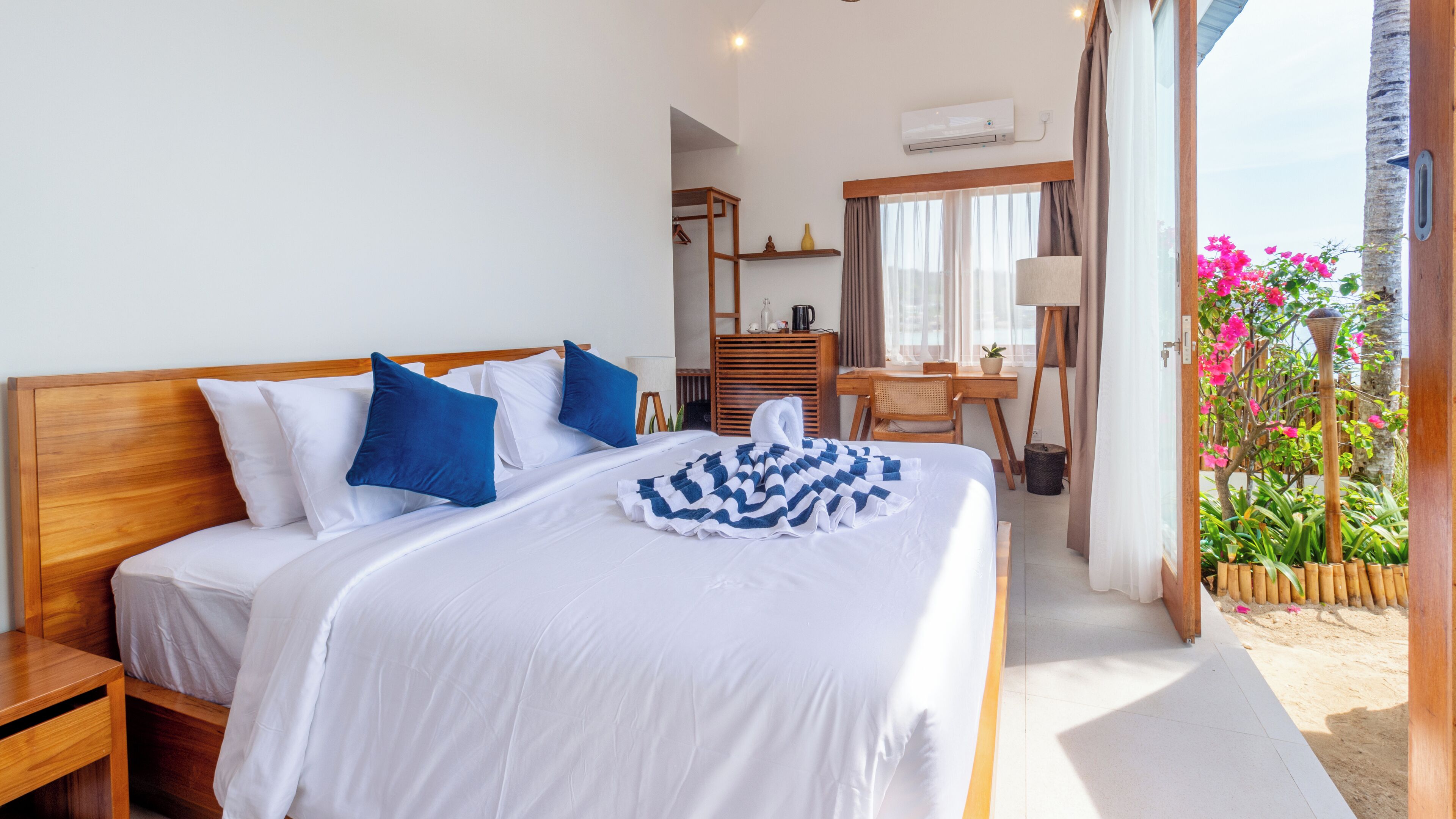 A neatly made bed with white and blue bedding, a wooden headboard, and a bedside table.