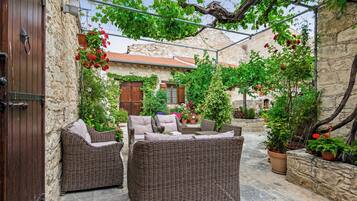 A courtyard with wicker furniture, stone walls, and potted plants.