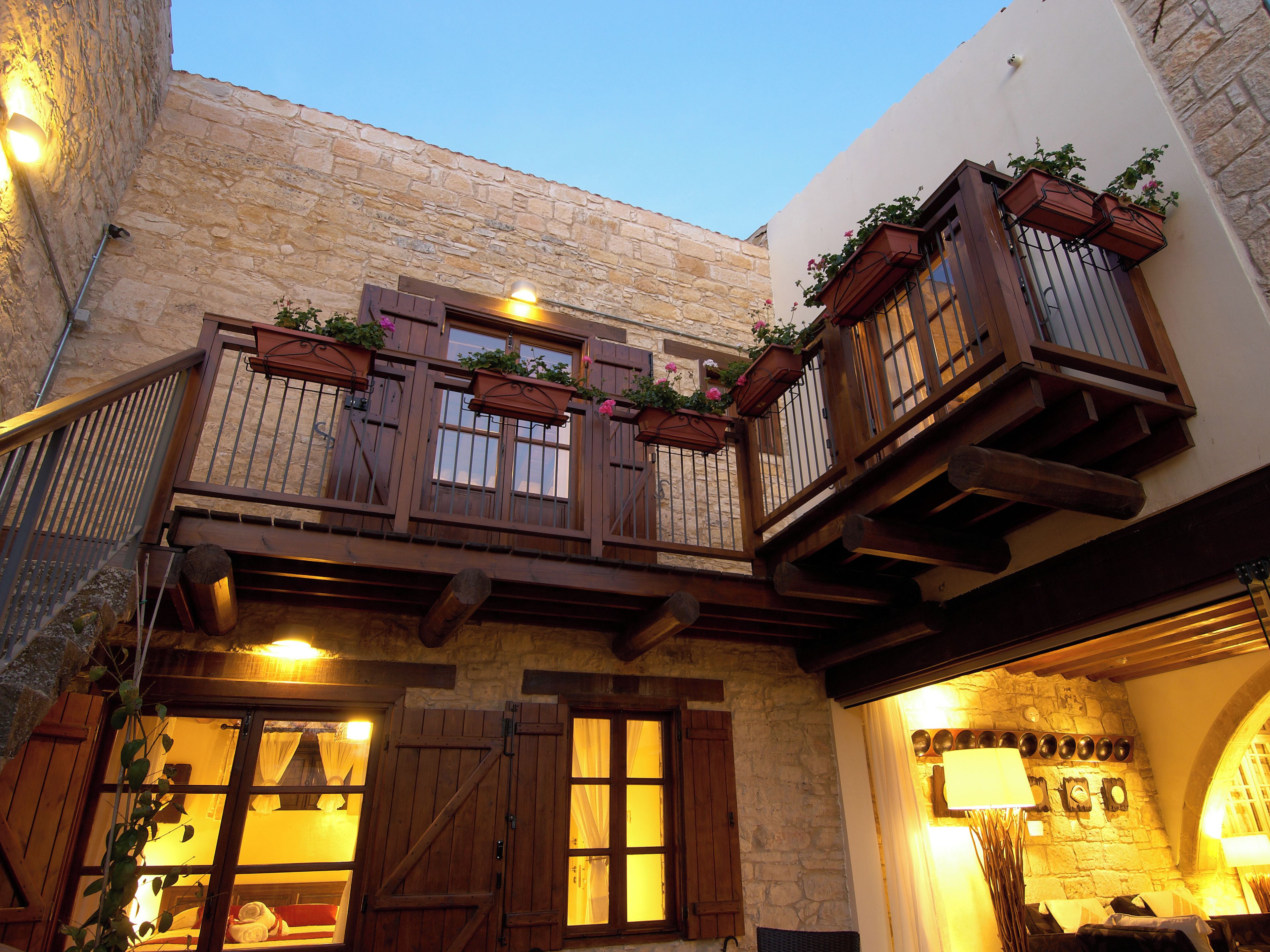 Un edificio tradicional con balcones de madera, paredes de piedra e iluminación cálida en el interior.