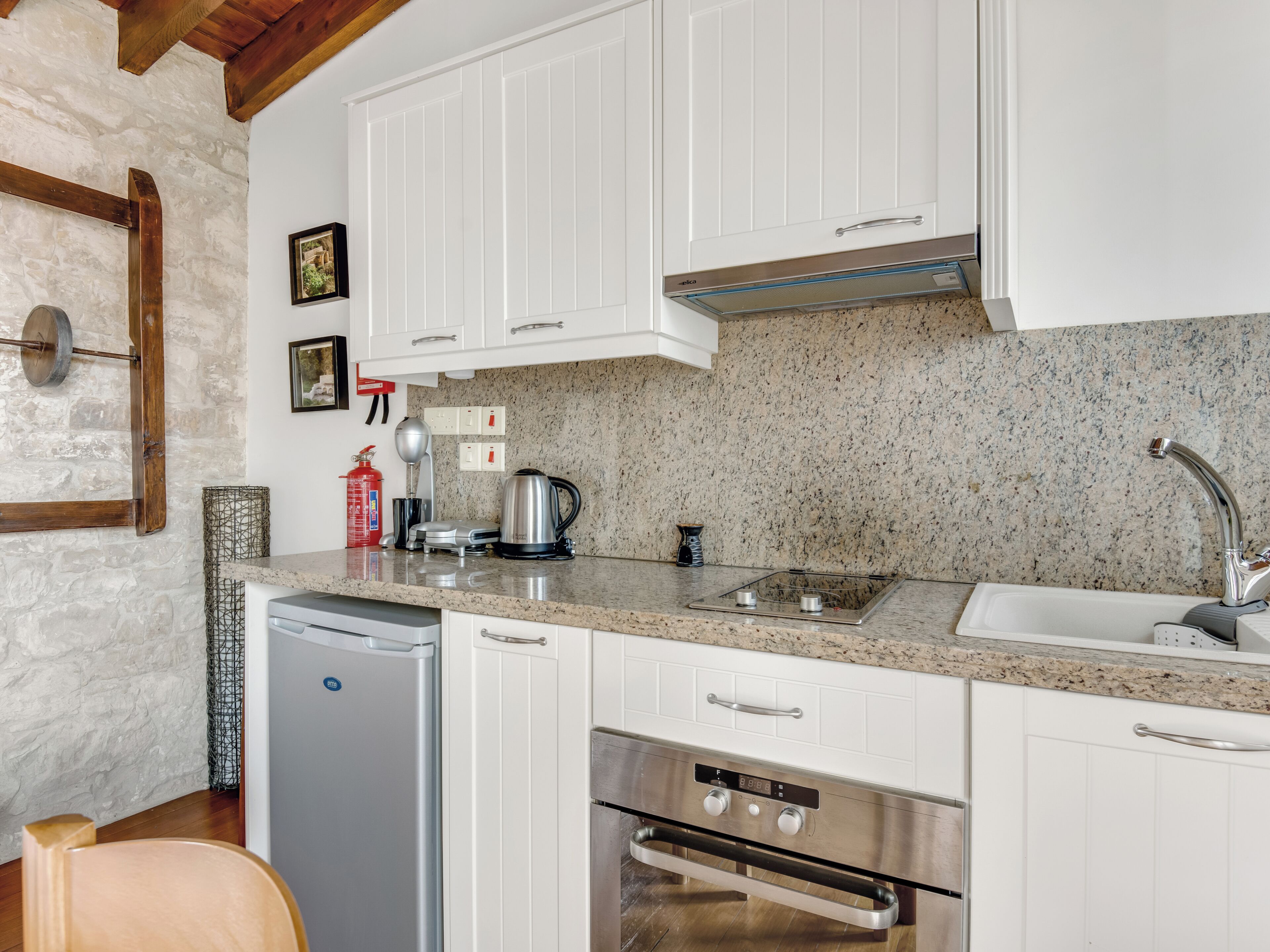 Una cocina moderna con gabinetes blancos, encimeras de granito, electrodomésticos de acero inoxidable y salpicadero de piedra.