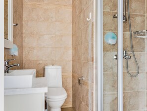 Een badkamer met toilet, wastafel en douchehoek.