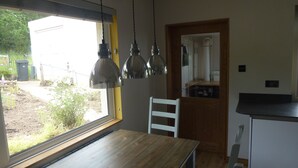 Una cocina con mesa de madera, una silla blanca y luces colgantes.