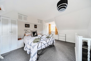 Een slaapkamer met een bed, een witte garderobe en een raam met gordijnen.