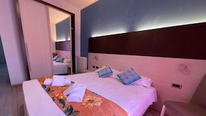 Habitación de hotel con una cama grande, una silla, un espejo y un radiador.