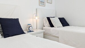 A hotel room with two beds, a bedside table with a lamp, a clock, and two framed pictures on the wall. - PANORAMIC sweet home (Finestrat)