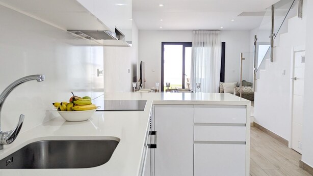 A modern kitchen with a central island, stainless steel sink, and a bowl of fruit. - PANORAMIC sweet home (Finestrat)