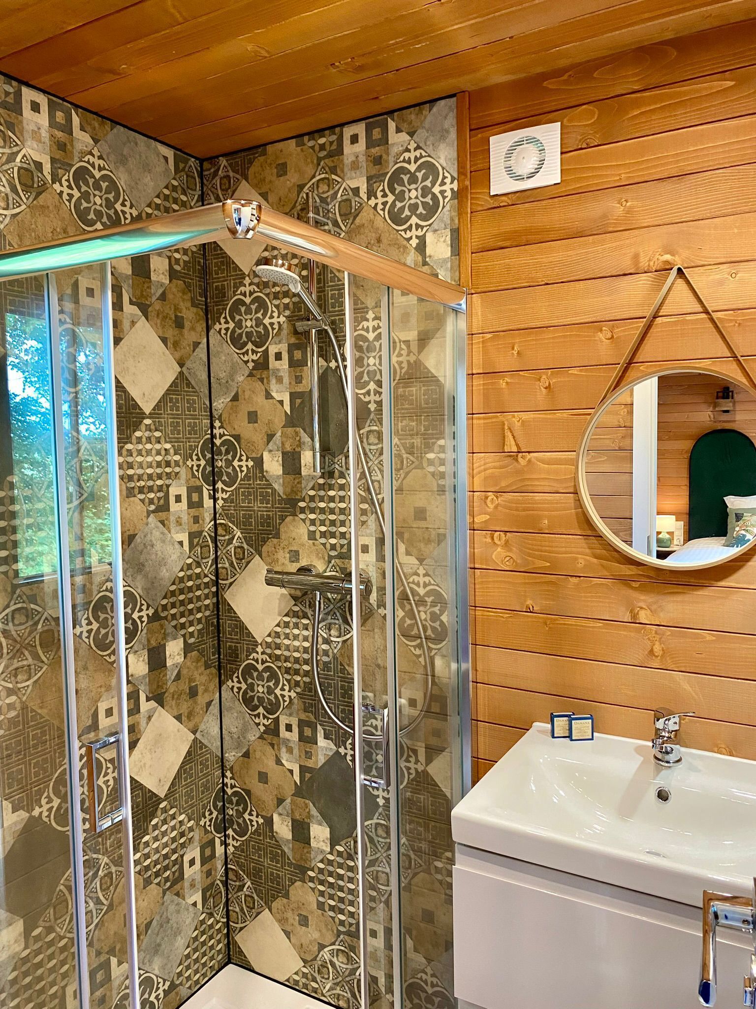 A shower with a glass door and a wooden ceiling.