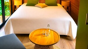 A wooden room with a bed, two wall-mounted lights, a round table with glasses, and a window with a view. - Hôtel Les Lodges De Vaugrigneuse (Vaugrigneuse)