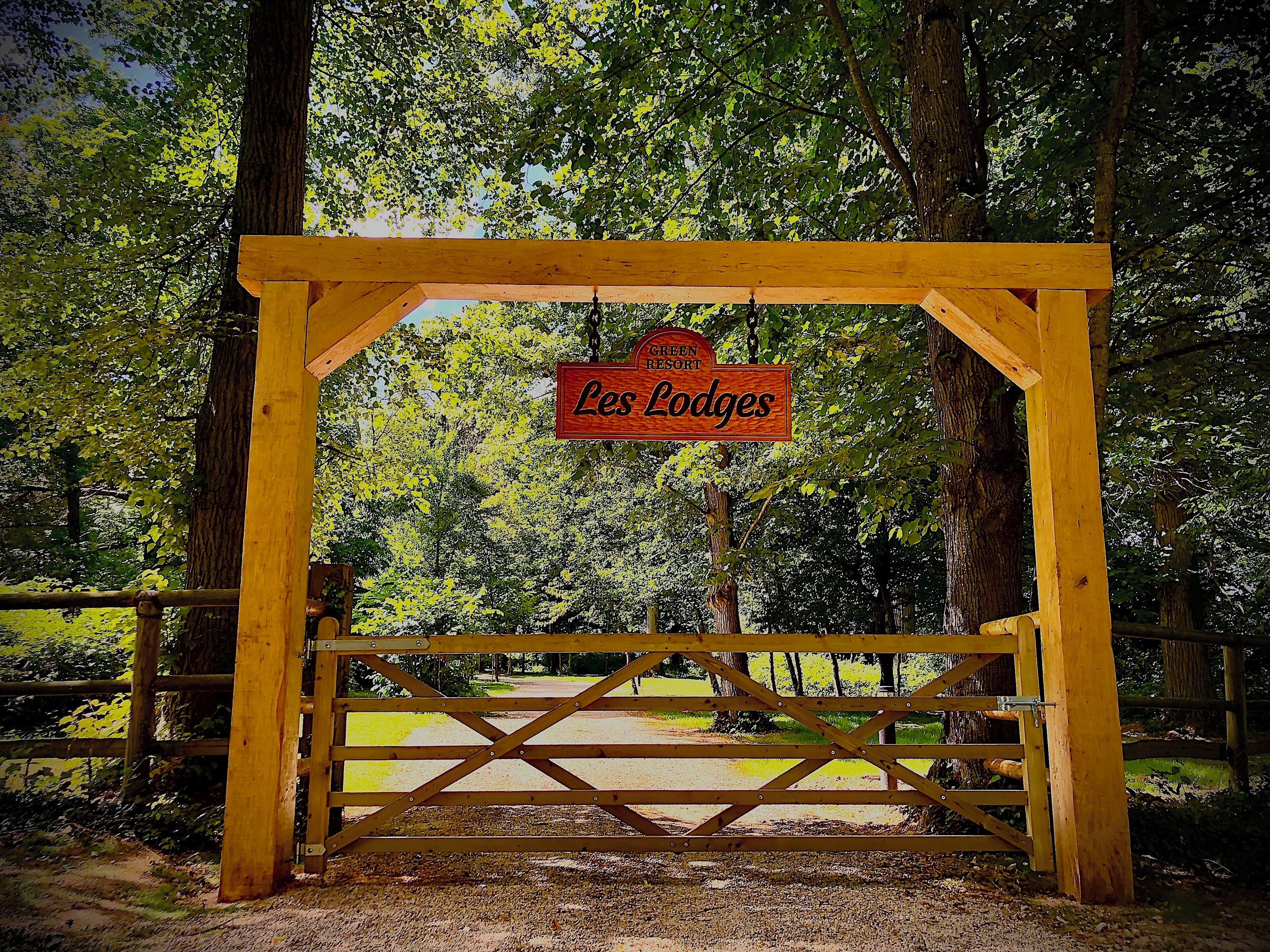 A wooden gate with a sign that reads 'Green Resort Les Lodges.'