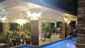 An indoor swimming pool area with a seating area and a dining section. - Natura Ravee Greenstay (Mae Taeng)