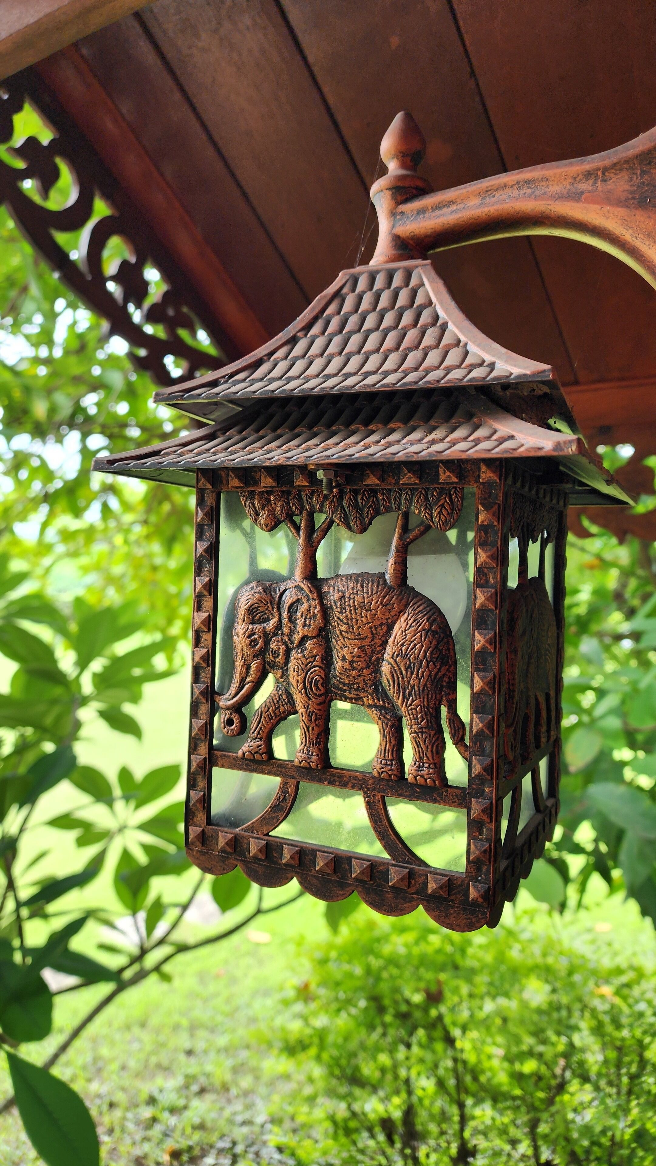 A lantern with an elephant design, hanging outdoors.