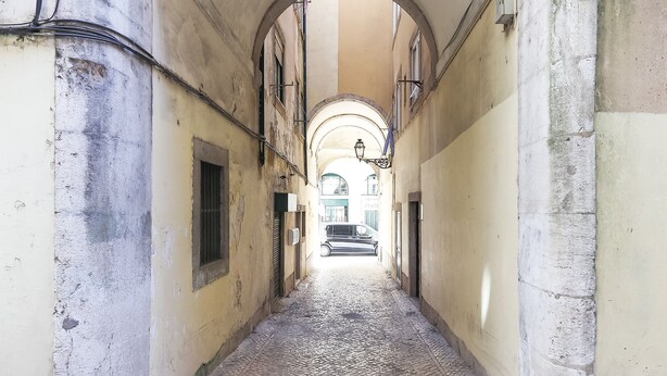 A narrow cobblestone alleyway with arched ceilings and a vehicle in the distance. - Santos Tiny Studio II by Homing (Lisbon)