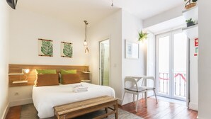 A bedroom with a bed, bedside table, bench, and a chair. - Santos Tiny Studio II by Homing (Lisbon)