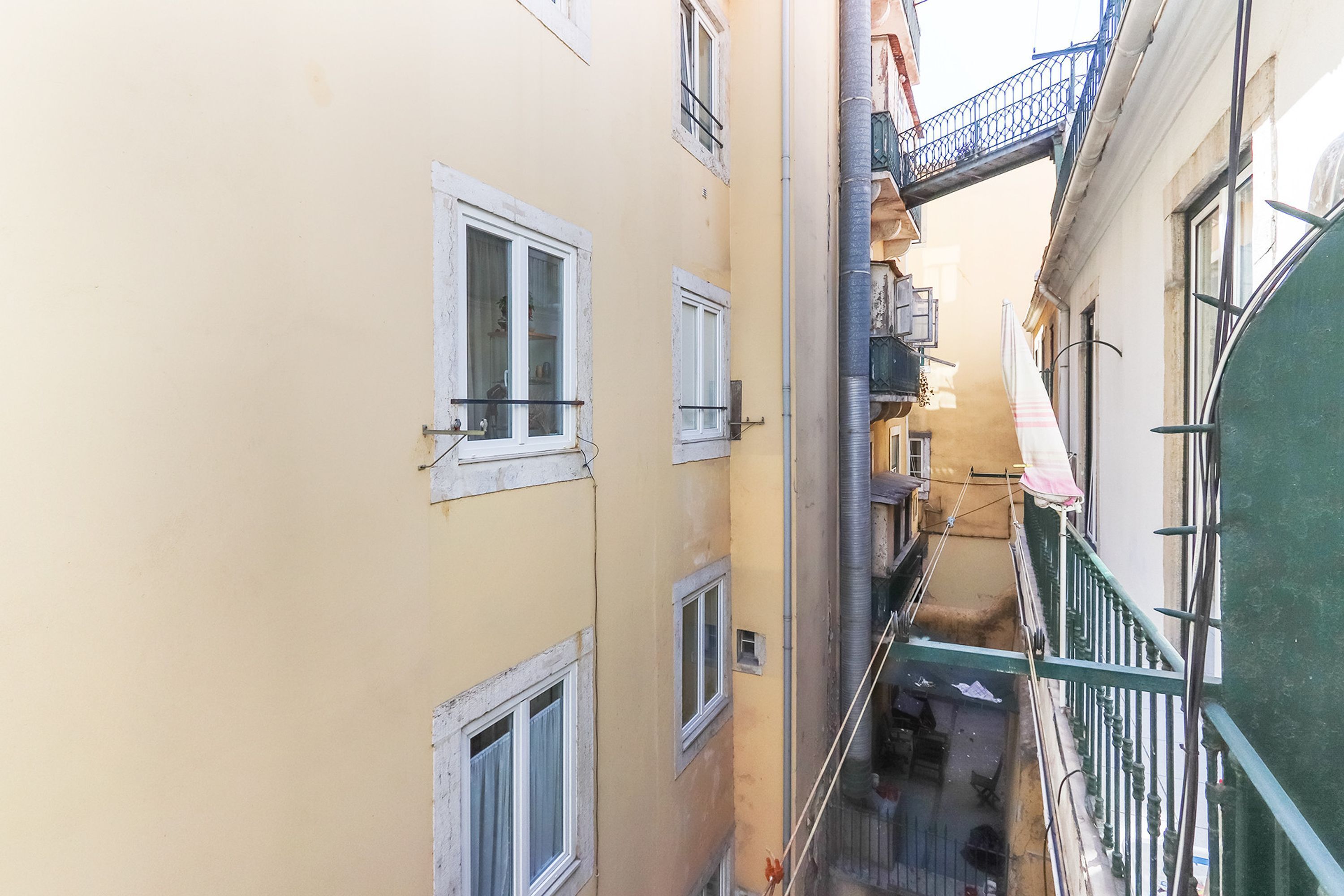 Un estrecho callejón entre edificios con balcones y una escalera visible.