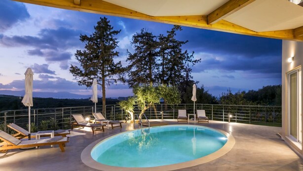 A rooftop pool with lounge chairs and umbrellas, surrounded by trees and a scenic view. - AeNaos Luxury Villa (Chania)