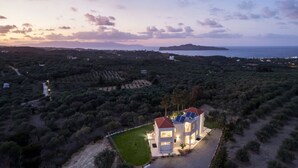 A coastal property with a large house featuring a red roof, solar panels, and a well-maintained lawn. - AeNaos Luxury Villa (Chania)