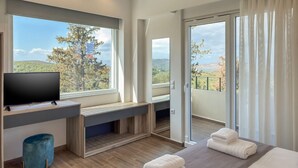 A modern hotel room with a large window, a flat-screen TV, a balcony, and a bed with towels. - AeNaos Luxury Villa (Chania)