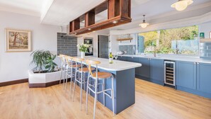 Une cuisine moderne dotée d’un îlot central, de tabourets de bar et offrant une vue sur l’extérieur.