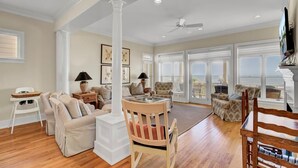 A spacious living room with a high ceiling, large windows, and a view of the outdoors. - Oceanfront | 3 Decks, Walk to Grand Pavilion Pools & Boardwalk (Isle of Palms)