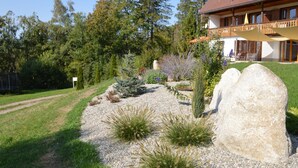 Uma casa com um jardim amplo, um caminho de cascalho e um deck de madeira.