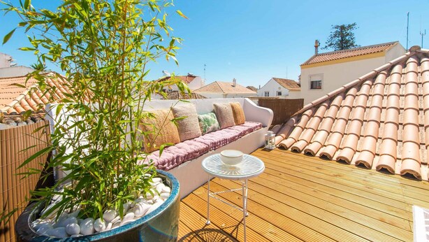 A rooftop terrace with a sofa, a small table, and a bamboo plant. - Casa Telhados | Historic Center | Private Terrace (Faro)